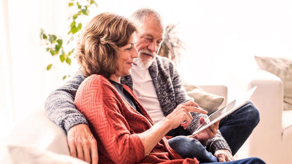 Senior couple with tablet sat in a chair