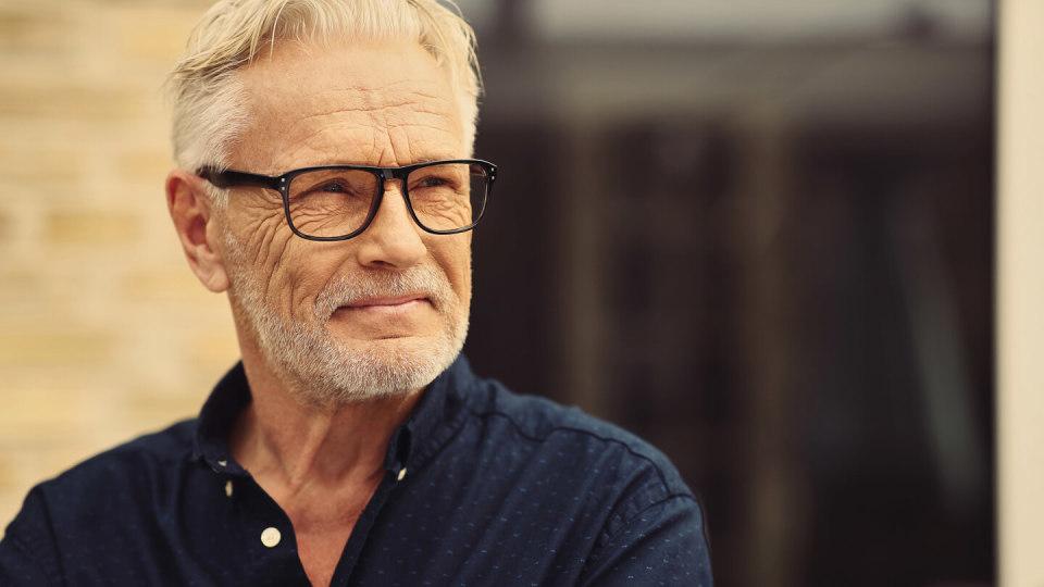 Senior man with blue shirt and glasses standing outside