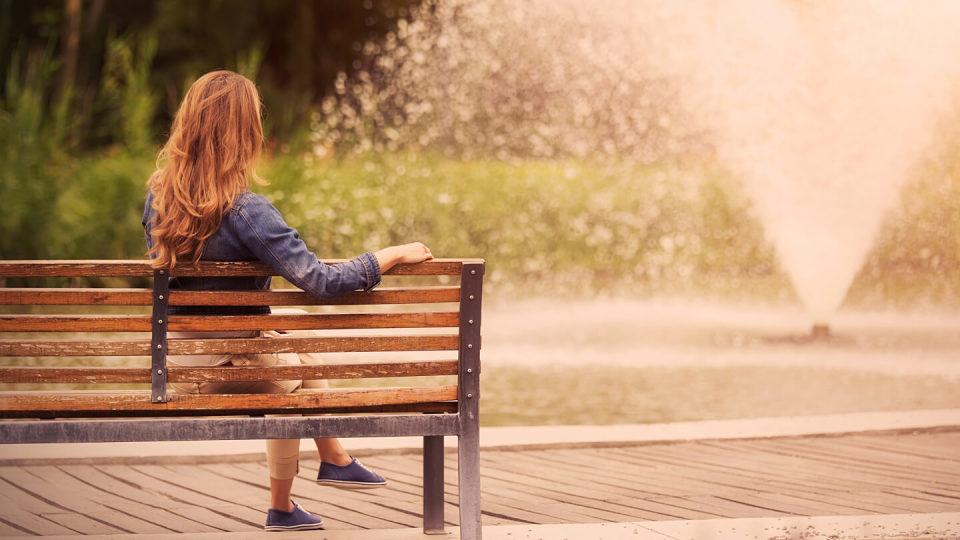 Young woman sitting on bench in park