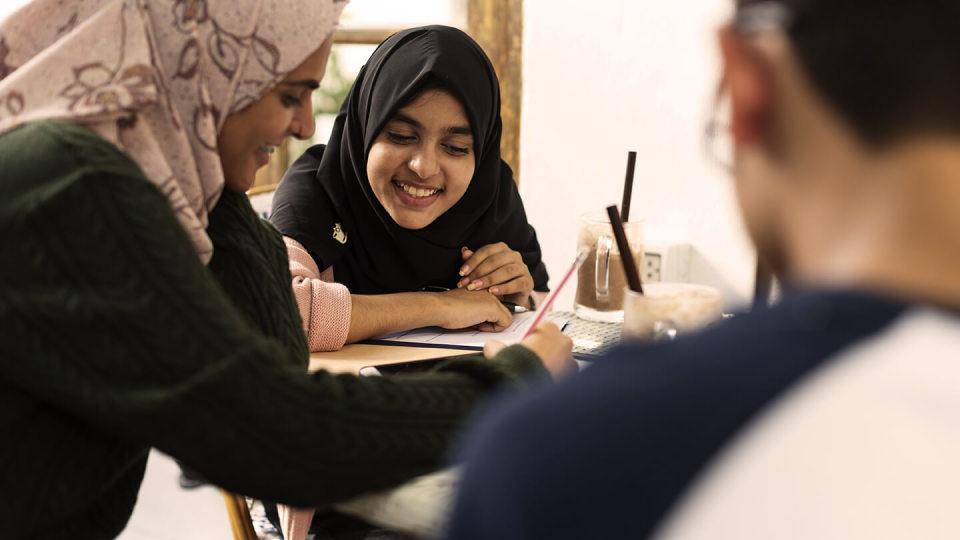 Three friends working round a table