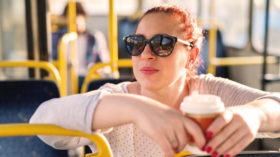 Young woman wearing sunglasses sat on a bus