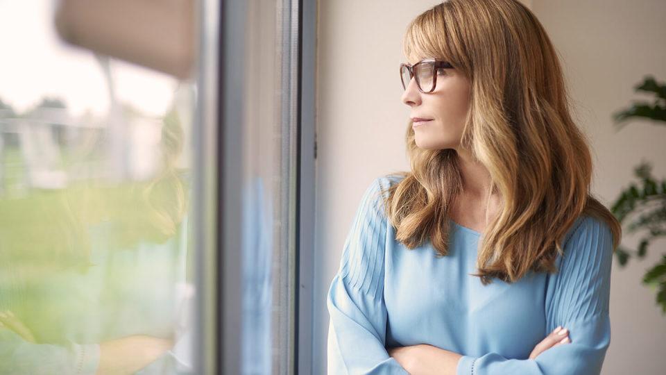 Woman with glasses stood by window