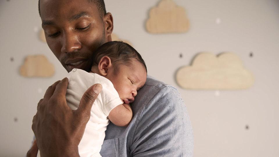 father holding new born in nursery