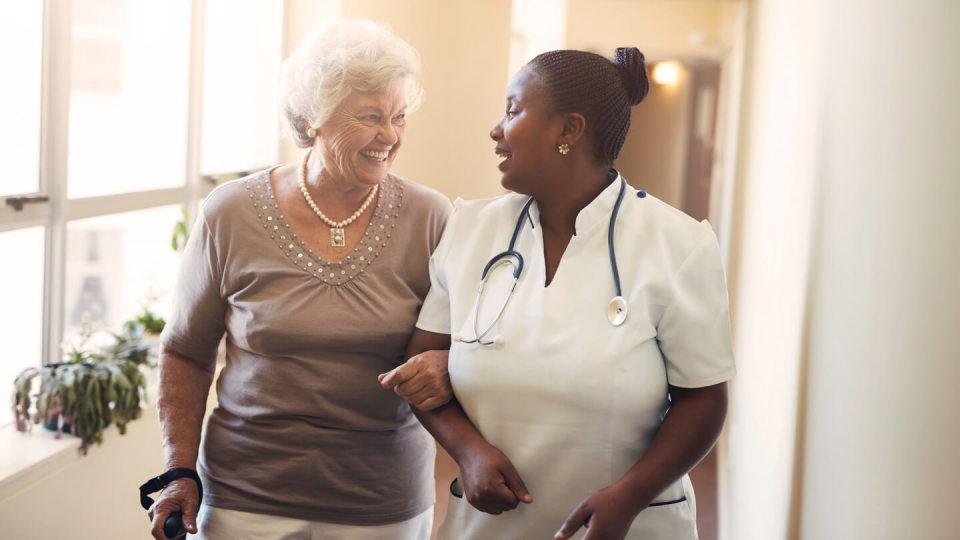 Happy nurse talking to elderly lady