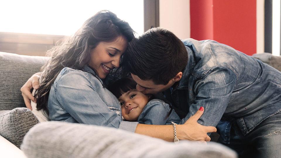 family hugging on sofa