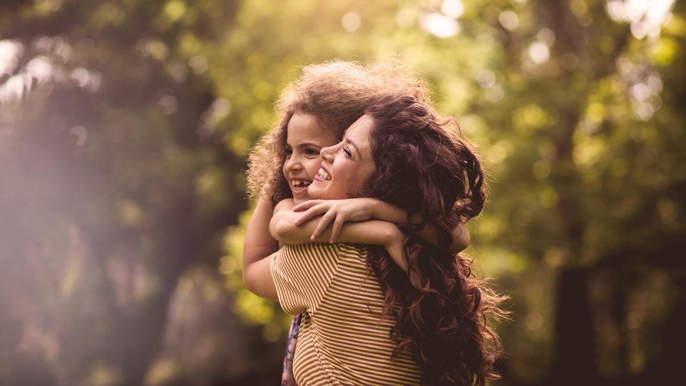 Woman hugging child under trees