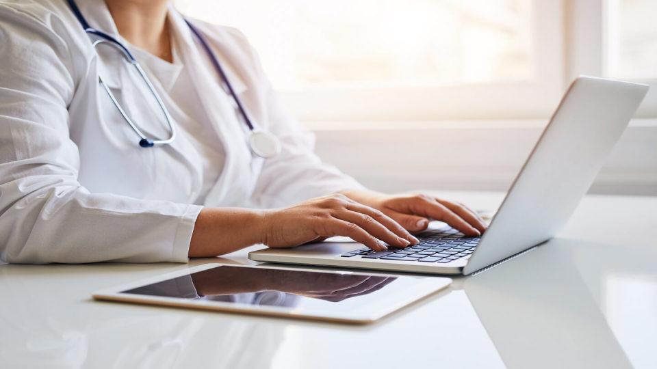 Medical professional typing on a laptop