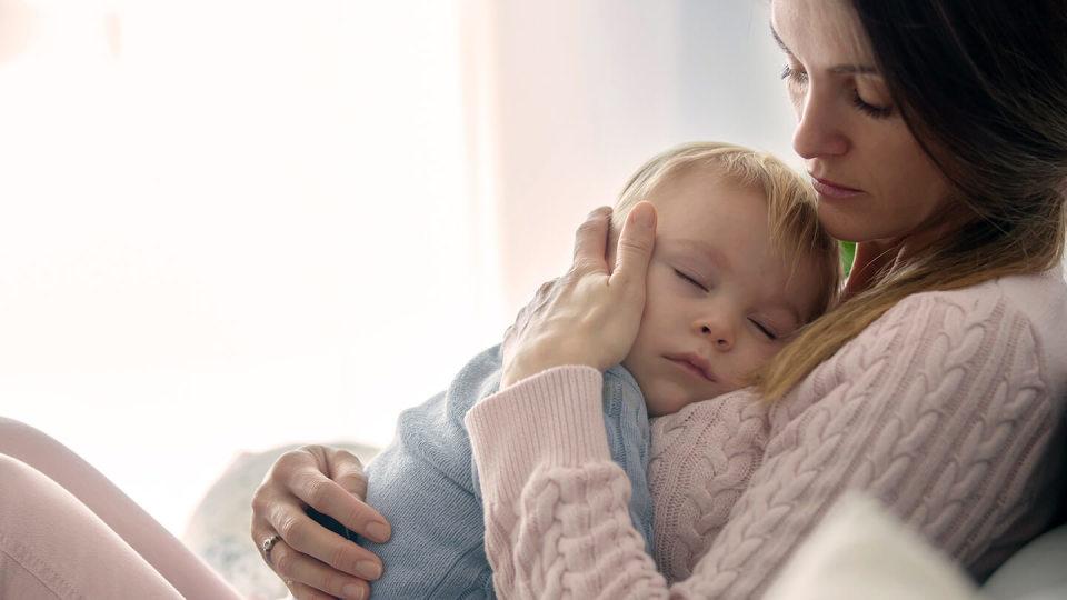 Young mother cuddling sleeping son