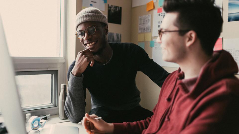 Two friends smiling at desk