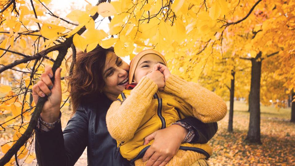 Mother holding young son under a tree