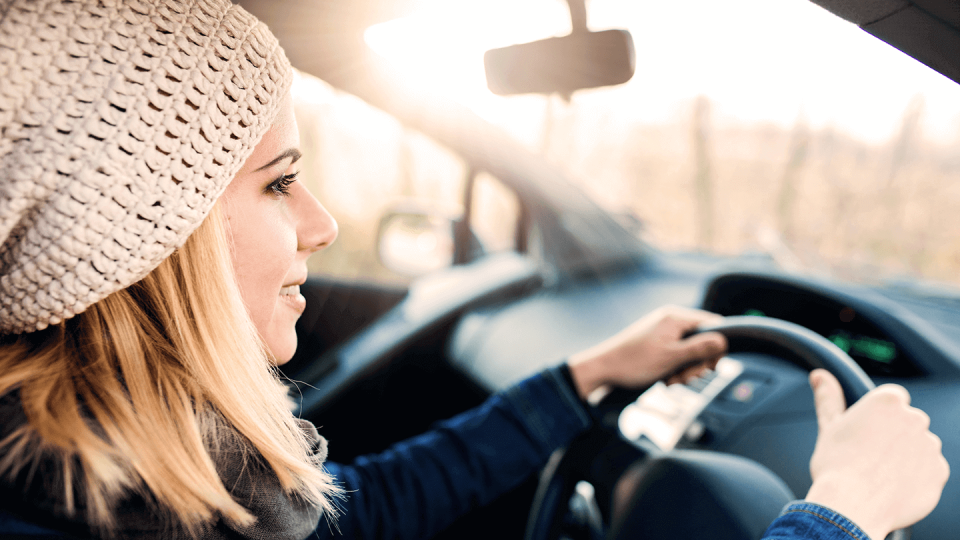 Woman in pink hat driving car	