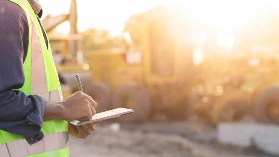 man working in construction writing on pad