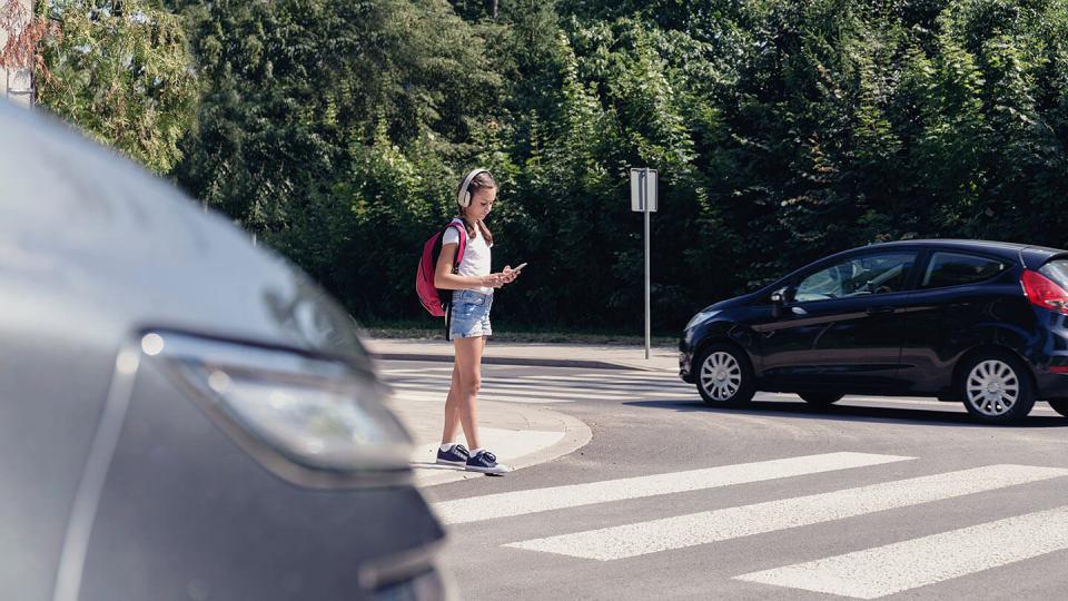 Young girl crossing at zebra crossing 	road 	traffic